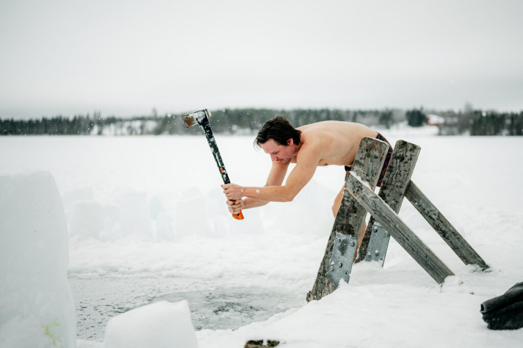 Chris Rauwendaal hakt een wak in het ijs tijdens een koude training om bruin vet te activeren en het lichaam te versterken in Fins Lapland.