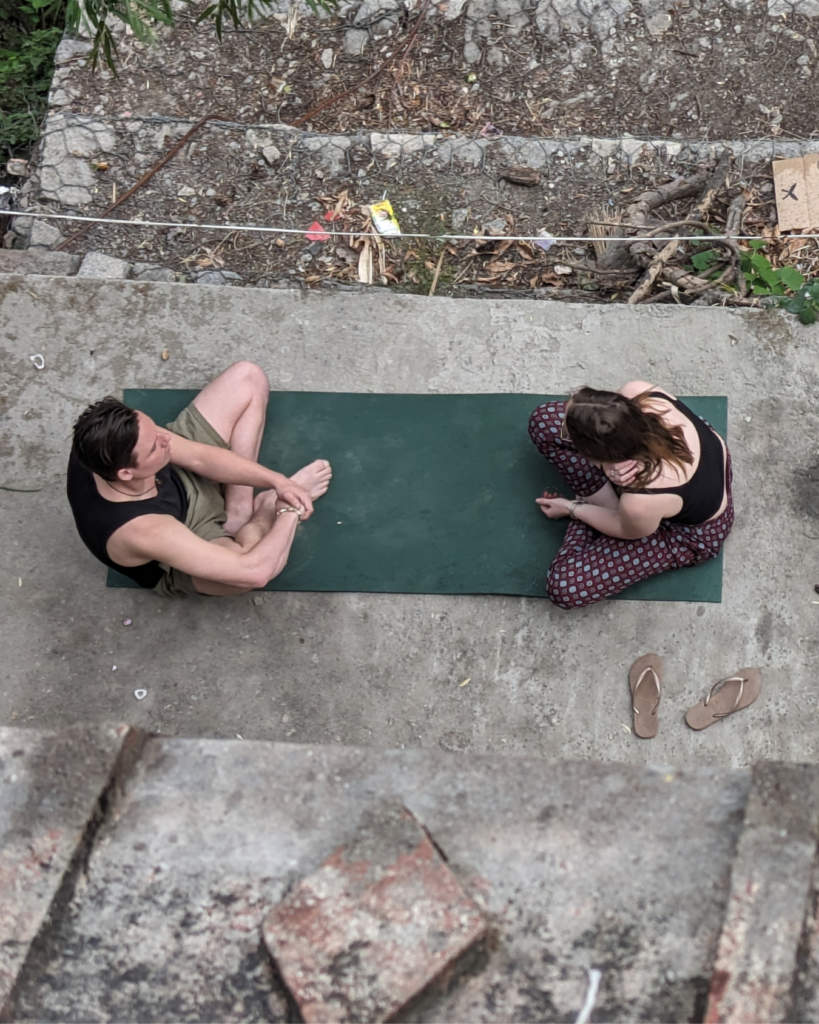 Chris Rauwendaal in een coachingsgesprek op een yogamat in de rauwe natuur van Nepal, symbool voor diepgaande transformatie en persoonlijke begeleiding.