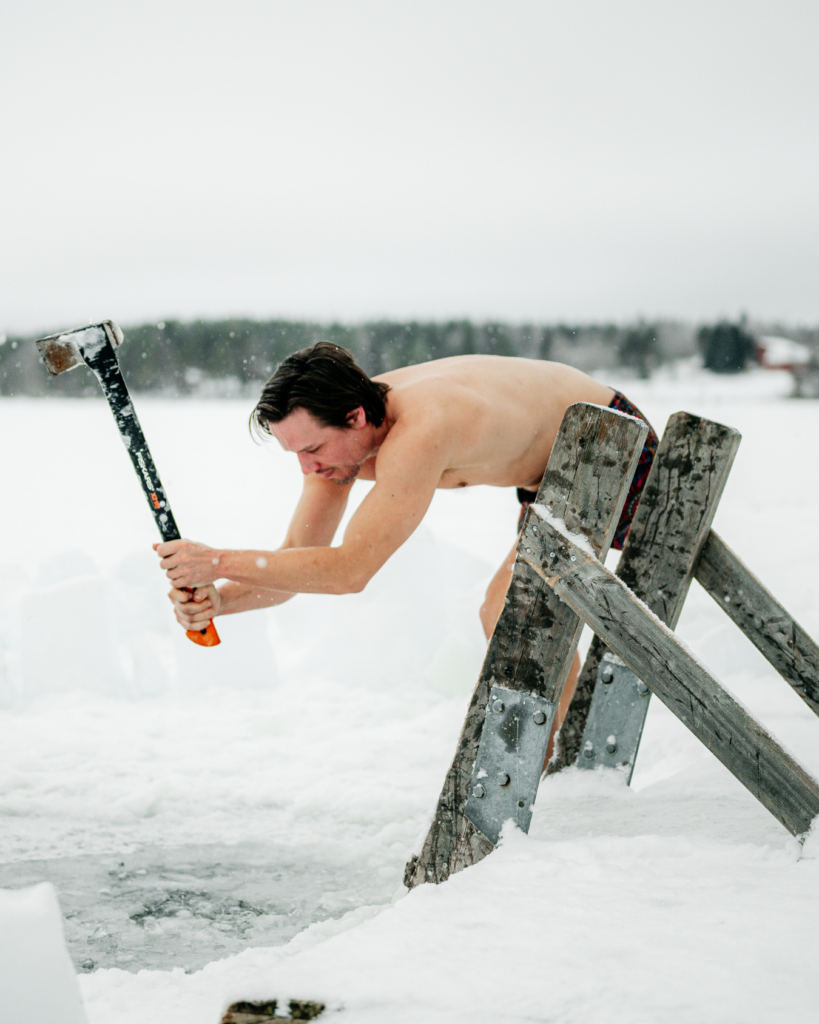 Chris Rauwendaal hakt een wak in het ijs tijdens een koude training om bruin vet te activeren en het lichaam te versterken in Fins Lapland.