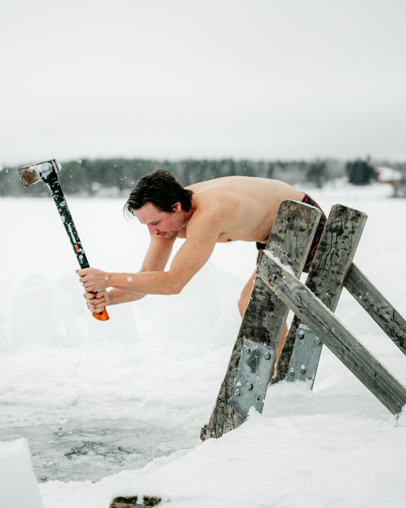 Chris Rauwendaal hakt een wak in het ijs tijdens een koude training om bruin vet te activeren en het lichaam te versterken in Fins Lapland.