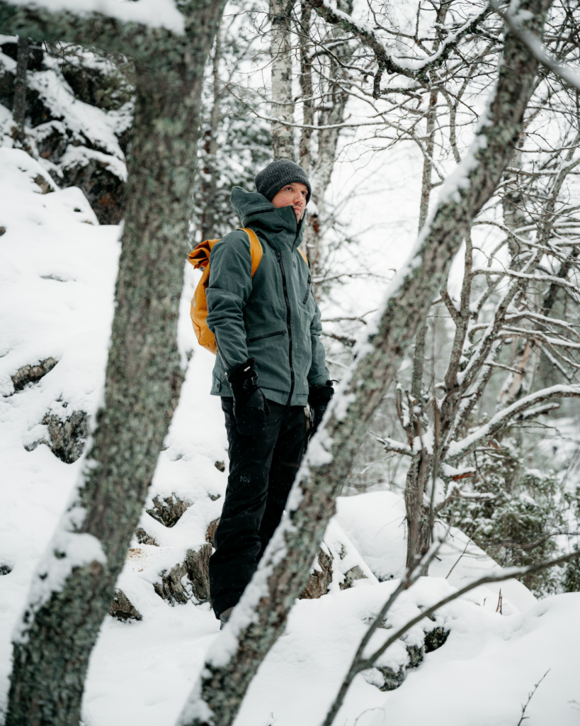 Chris Rauwendaal staand in een besneeuwd bos in Fins Lapland, op reflectieve winterwandeling – symbool voor innerlijke verandering en zelfontdekking.