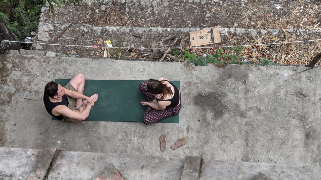 Chris Rauwendaal in een coachingsgesprek op een yogamat in de rauwe natuur van Nepal, symbool voor diepgaande transformatie en persoonlijke begeleiding.