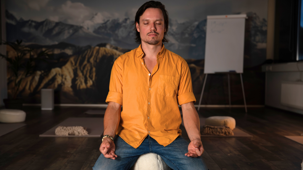 Chris Rauwendaal zit in lotushouding ter begeleiding van het herstellen van een verstoord adempatroon door chronische hyperventilatie