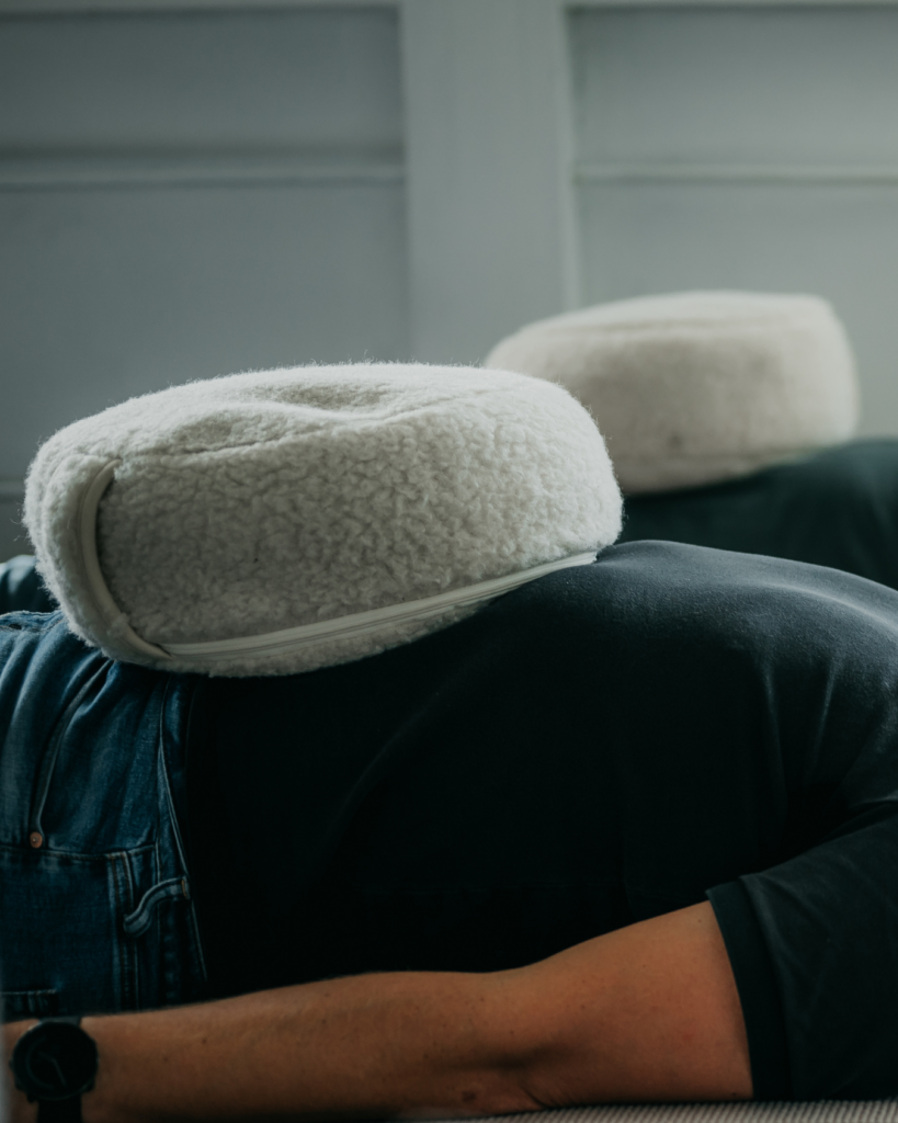 Persoon liggend met ademkussen op de buik – symbool voor ademobservatie en optimale ademfrequentie.