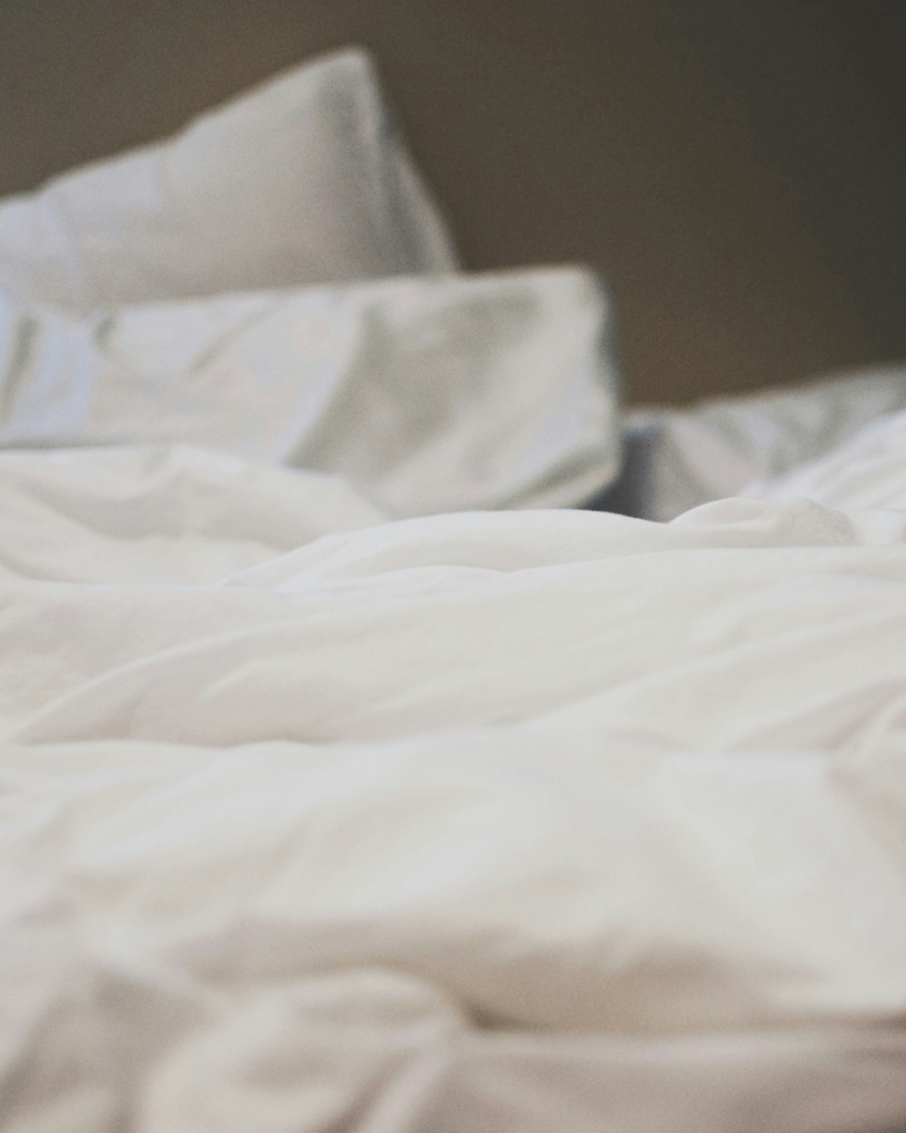 Witte lakens op een bed – verwijzing naar slaapkwaliteit, mondtape en het belang van goede nachtrust.